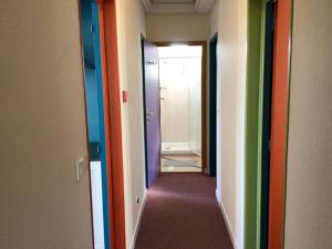 un couloir avec des portes colorées différentes et un couloir avec un couloir dans l'établissement Hôtel Bellevue Bagnoles Normandie, à Bagnoles-de-l'Orne