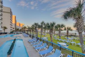 een zwembad met ligstoelen en palmbomen bij Boardwalk Resort: Ocean Breeze Retreat in Myrtle Beach