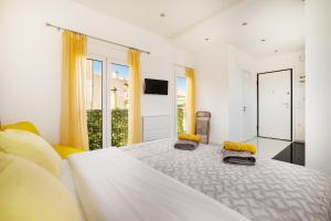 a white bedroom with a large bed with yellow curtains at Posh hood Rooftop with balconies in Athens
