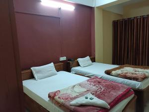a small room with two beds with white sheets at Hotel Yuvraj Palace in Chutiyā Mīrigaon