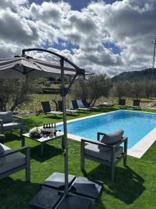 een zwembad met stoelen en een tafel en een parasol bij Quinta de Gandarem in Torre de Moncorvo