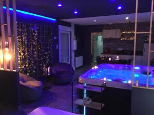 un soggiorno con vasca in una camera con luci viola di Lov'Infini a Mers-les-Bains