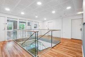 escalera de cristal en una habitación blanca con suelo de madera en BB-Hotel Aarhus Havnehotellet, en Aarhus
