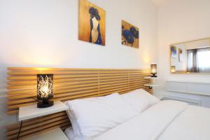 Un dormitorio con una cama blanca con cabecero de madera. en Primopiano - Fargorida 6, en Milán