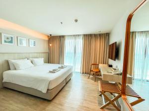 a hotel room with a large bed and a desk at Zand Morada Pattaya in Jomtien Beach