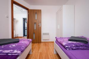 2 łóżka w pokoju z fioletową pościelą w obiekcie Apartamenty Plazowa w Darłówku