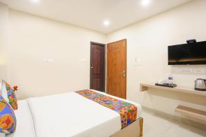 FabHotel Hari Kunj في فاراناسي: غرفة بيضاء فيها سرير وتلفزيون