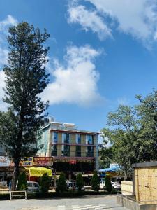 a tall building with a tree in front of it at Hotel natraj pachmarhi in Pachmarhī