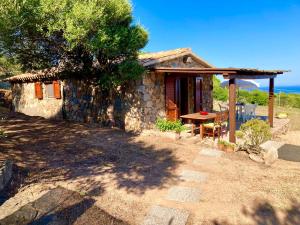 una pequeña casa de piedra con una mesa delante en Le Verande di Isola Rossa, en Isola Rossa