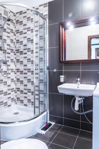a bathroom with a tub shower and a sink at TATRYSTAY Apartments Tatranska in Veľká Lomnica