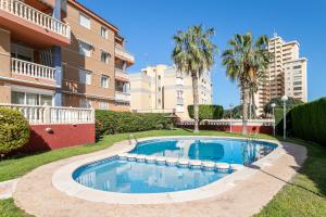 - une piscine en face d'un bâtiment avec des palmiers dans l'établissement Juan de la Cierva Playa, à El Campello
