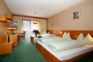 a hotel room with two beds and a table at Hotel Alpina Regina in Biberwier