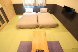 um quarto com duas camas e uma televisão no chão em KYOSTAY Iroha Komichi em Quioto