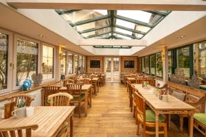 a restaurant with wooden tables and chairs and a skylight at Landhaus Hotel Wolfratshausen in Wolfratshausen