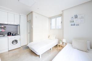 a white room with two beds and a kitchen at Ehwa Blossom in Seoul