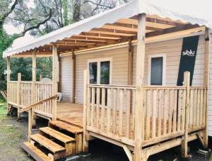 a wooden cabin with awning on a deck at Mobil-Home 3 Chambres, TOUT CONFORT, Option "DRAPS FOURNIS" Disponible ! in Pont-Aven