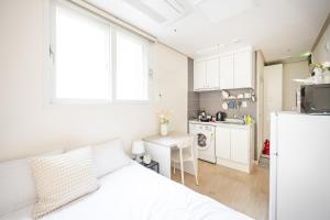 a white bedroom with a white bed and a kitchen at Ehwa Blossom in Seoul