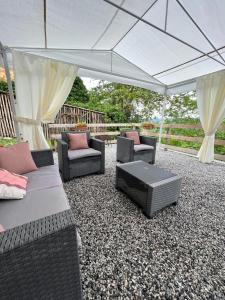 a patio with couches and chairs under a tent at Casa vacanze Monte in Castellino Tanaro