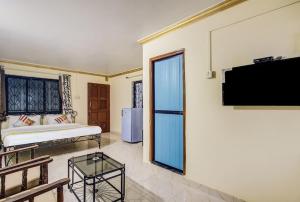 Super OYO Pravin Holiday Homes في كالانغيُت: غرفة معيشة مع سرير وتلفزيون على جدار