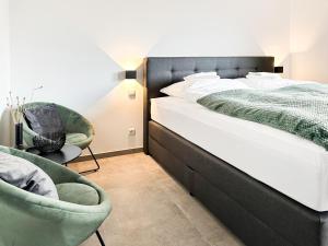 een slaapkamer met een groot bed en 2 stoelen bij SI-View Doppelzimmer mit Stadtblick Zimmer 21 in Siegen