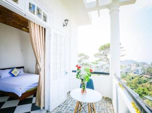 a room with a bed and a table with flowers on a balcony at Villa Hằng Nga 3 in Ấp Ða Lợi +16 photos