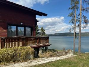 a log cabin with a deck and a view of the water at Villa Iskar Lake in Shtarkelovo Gnezdo