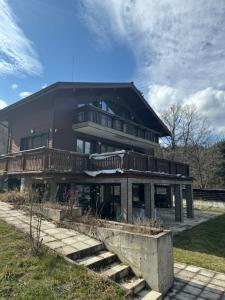 a large house with a balcony and stairs at Villa Iskar Lake in Shtarkelovo Gnezdo