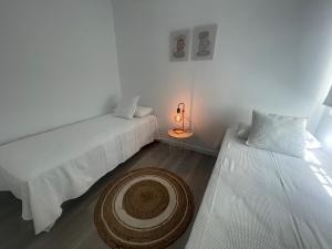 ein Zimmer mit zwei Betten und einem Tisch mit einer Lampe in der Unterkunft White Serenity in Playa Honda