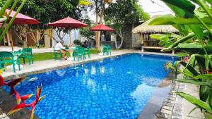 a swimming pool with chairs and tables and umbrellas at Vamana Bangsal in Pawenang