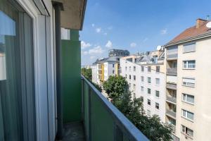 einen Balkon mit einer grünen Wand und einigen Gebäuden in der Unterkunft HM • Stylish 1BR Escape, City Quick in Wien