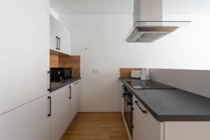 eine Küche mit weißen Schränken und einer schwarzen Arbeitsplatte in der Unterkunft HM • Stylish 1BR Escape, City Quick in Wien