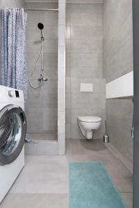 a bathroom with a toilet and a shower and a washing machine at Apartmán Josefská in Brno