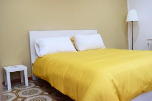een geel bed met 2 kussens en een gele deken bij La Perla in Isola delle Femmine