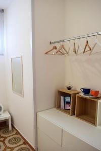 een kamer met witte muren en een plank met hangers bij La Perla in Isola delle Femmine