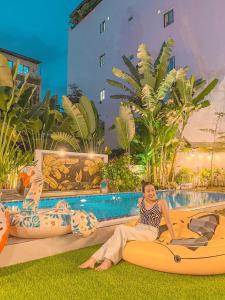 a woman sitting on a surfboard next to a pool at Chuỗi Villa 12 Ngủ - Trung Tâm Bãi Cháy in Ha Long