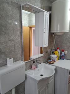 een badkamer met een witte wastafel en een spiegel bij Apartment Lucky Lu in Bar