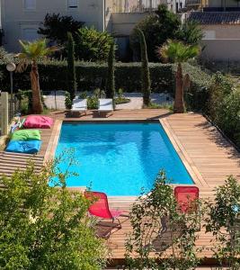 een zwembad met 2 stoelen en een houten terras bij Romantic Tiny House with private terrace and shared pool in Bessan