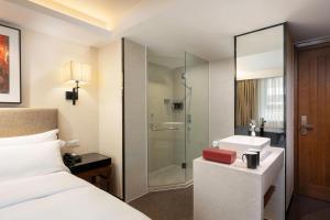 a hotel room with a bed and a sink and a shower at Sanya Great East Sea Junting Hotel in Sanya