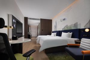 ein Hotelzimmer mit 2 Betten und einem TV in der Unterkunft Hampton by Hilton Shenzhen Nanshan Science and Technology Park in Shenzhen