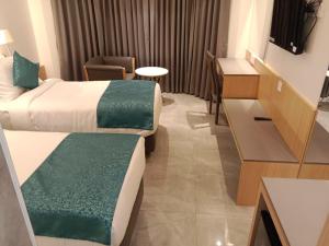 a hotel room with two beds and a desk at Coronet The Boutique Hotel in Pune