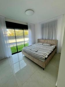 a bedroom with a large bed and large windows at בית בים in Netanya
