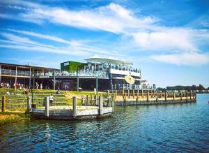 a pier on a lake with a building and people at Bull Rush Retreats luxury hot tub lodge at Tattershall Lakes in Tattershall