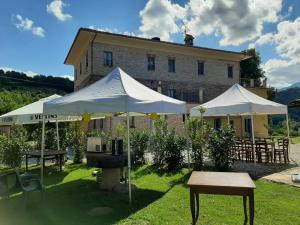 Montatteglia的住宿－Agriturismo Antica Corte，房屋前的两把白色遮阳伞