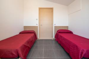 two beds in a room with red sheets at RESIDENCE TWIGHA in Martinsicuro