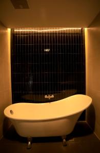 a bath tub in a bathroom with a black tiled wall at HABI Surawong-Silom in Bangkok