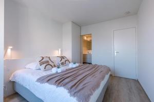 een witte slaapkamer met een groot bed met kussens bij Bright and spacious apartment with stunning views! in Knokke-Heist