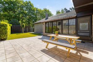 a patio with a wooden table and a bench at Huswell - Holiday home in the greenery of Limburg in Houthalen-Helchteren