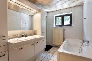 y baño con 2 lavabos, bañera y espejo. en Holiday home in the greenery of Limburg, en Aan de Wolfsberg