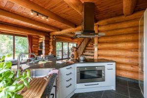 Cabaña de madera con cocina con fogones y fregadero. en Beautiful log home with stunning views en Zottegem