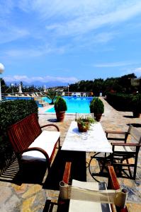 un patio con mesa, sillas y piscina en Golden Apartments, en Agios Nikolaos